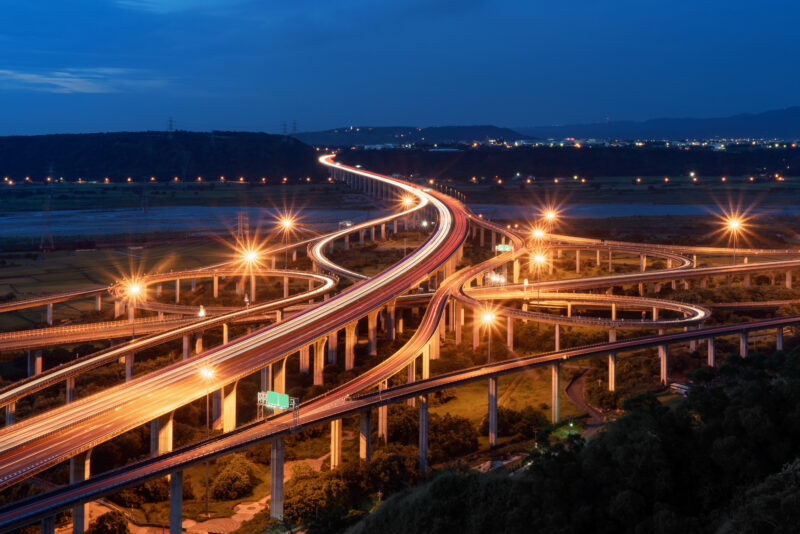 Aerial view of cars driving on complex highway or freeway. Bridge roads or streets in structure of architecture and transportation concept. Top view. Urban city, Taichung at night, Taiwan.