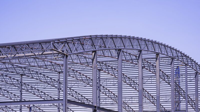 metal-curve-roof-beam-columns-outline-new-warehouse-building-structure-construction-site-scaled